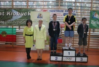 Trzech chłopców na podium w towarzystwie opiekunów