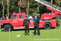 Dwóch strażaków na tle wozu strażackiego