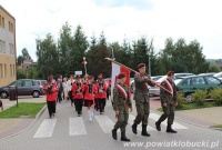 Polska flaga niesiona przez trzech umundurowanych chłopaków ulicami mias